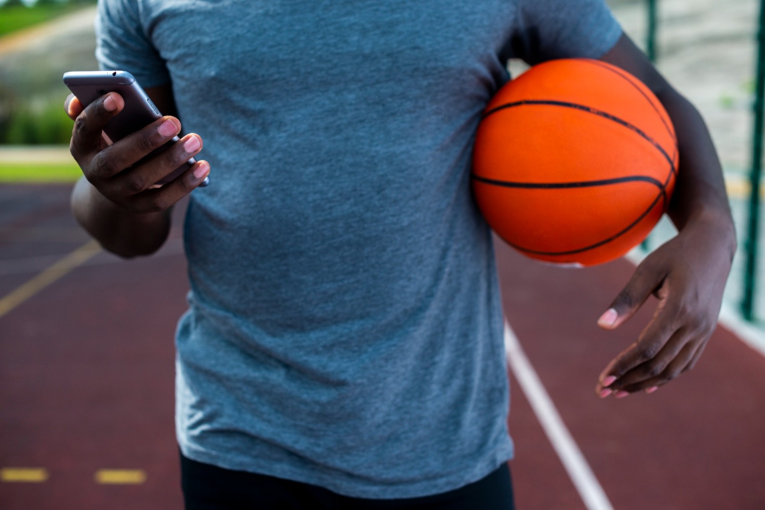 Homem com bola de basquete e celular - Foto: Freepik - Como Apostar no NBB?